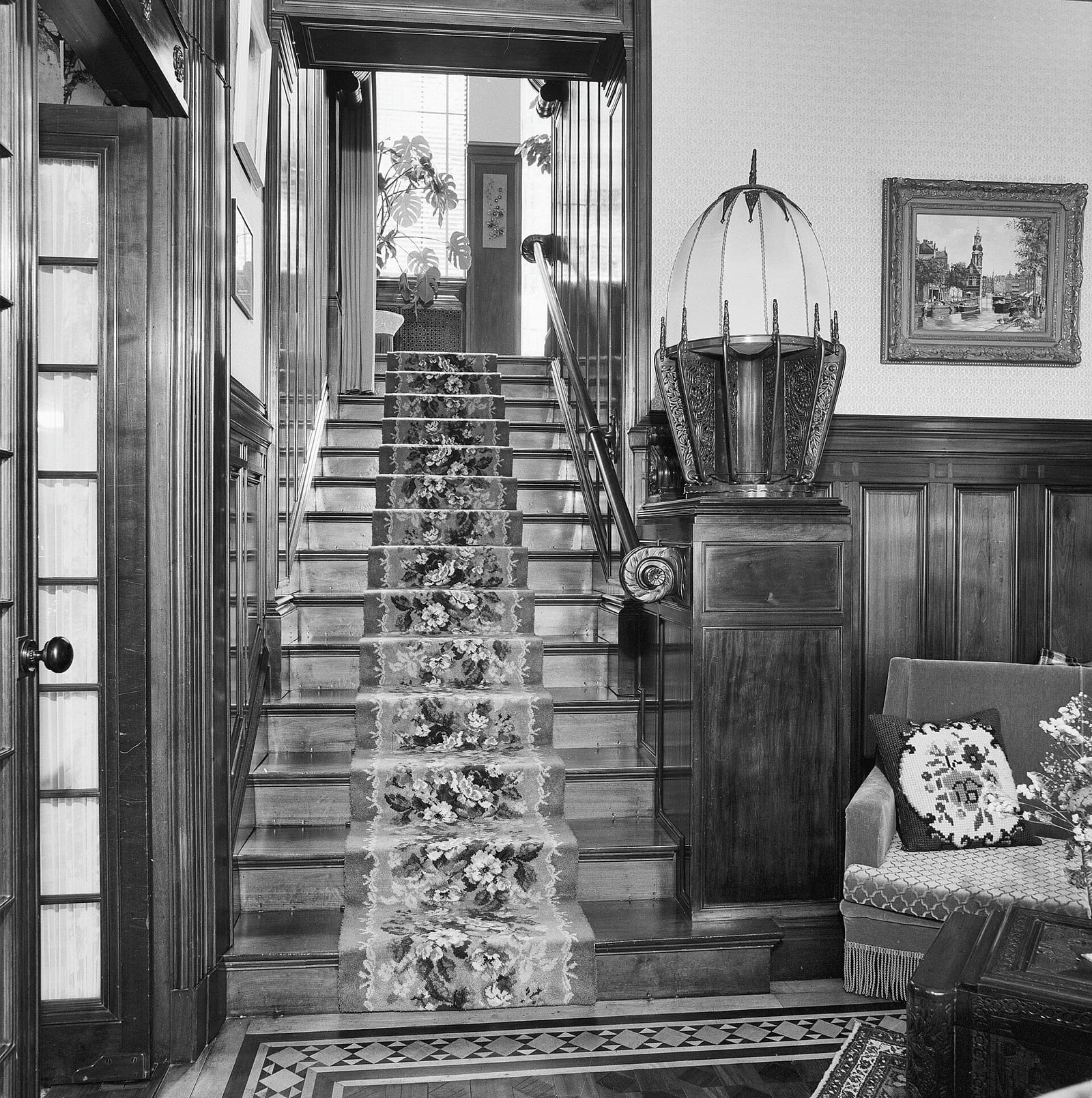Archive photograph of a panelled staircase and landing inside a villa in Bloemendaal, with a framed picture hung on the landing wall.