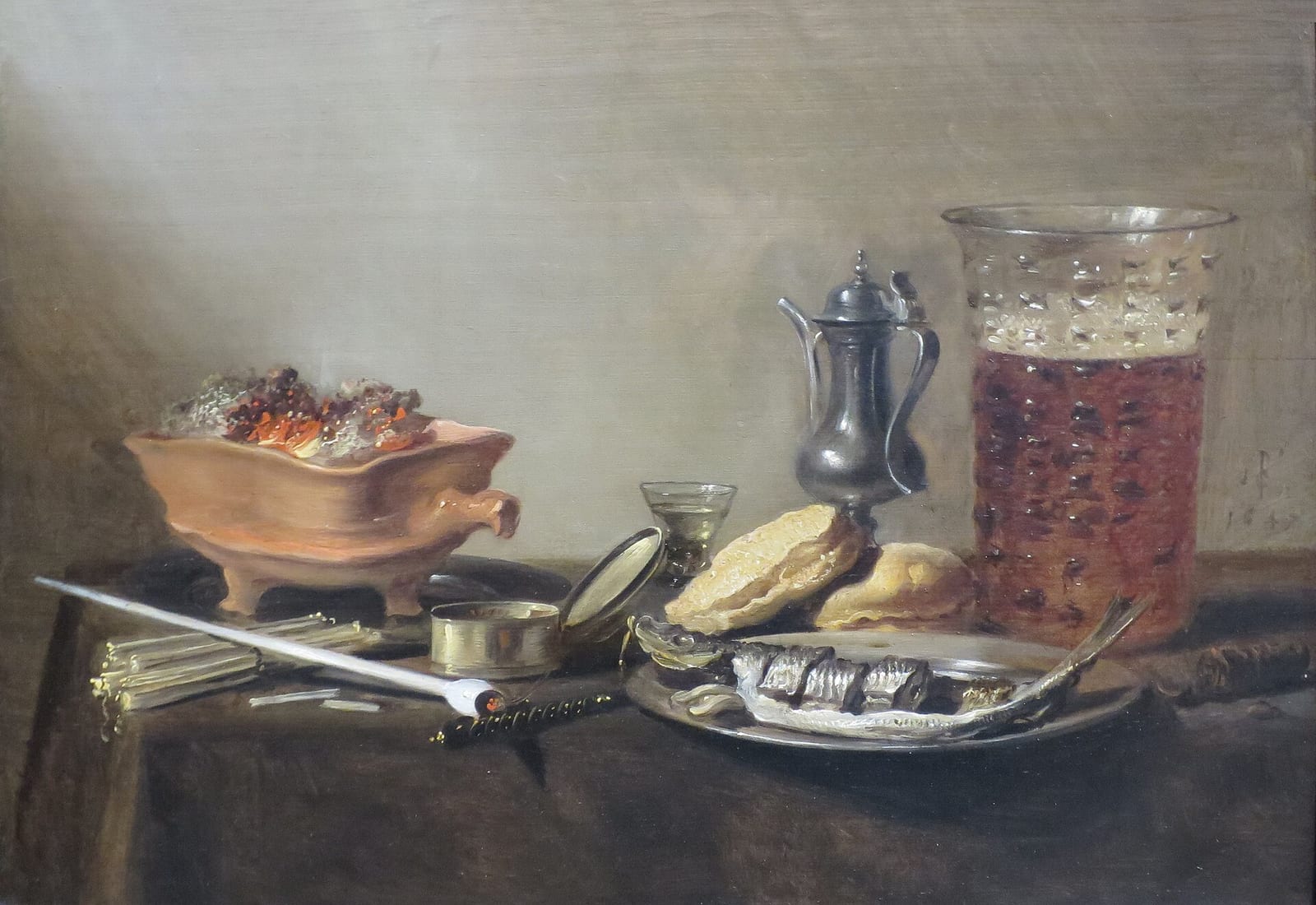 Still life by Pieter Claesz with a pewter jug, a glass of beer, bread, herring and a knife on a table against a plain wall.