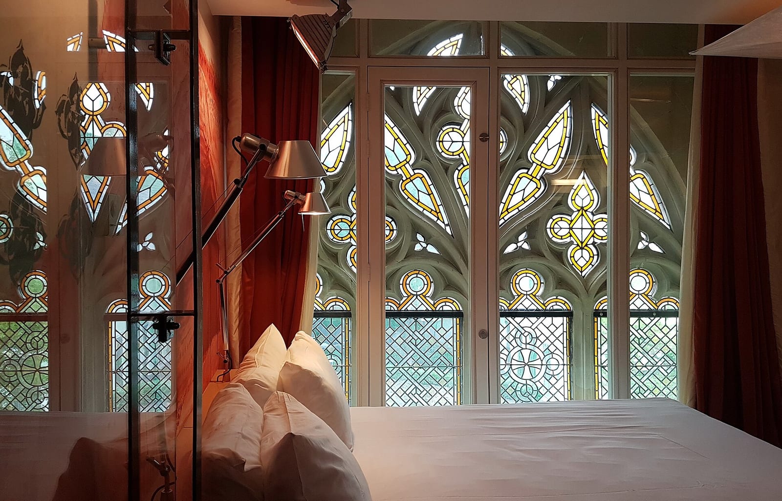 A guest room in the Kruisherenhotel in Maastricht, its bed set against the stained-glass windows of the former monastery church.