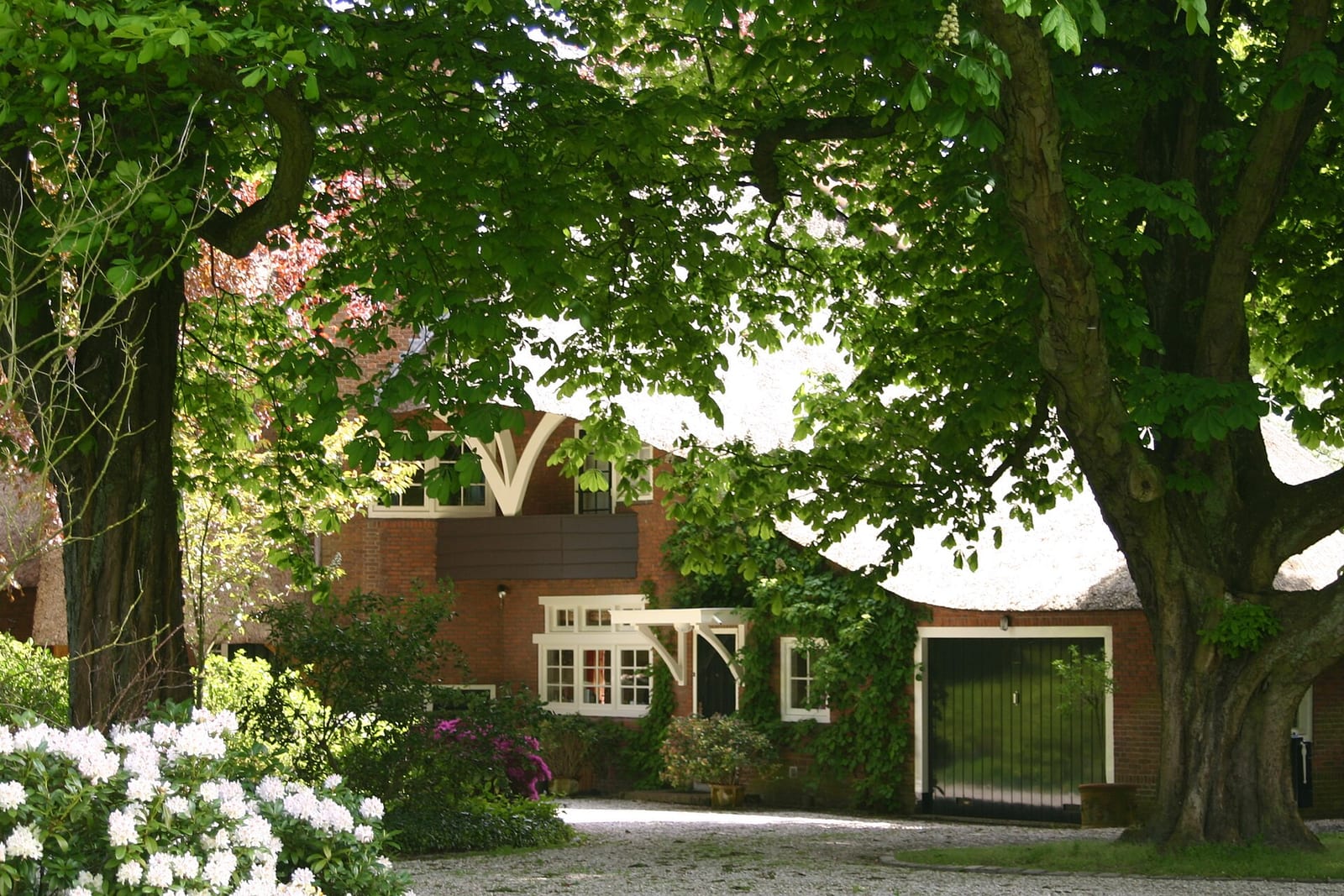 A brick villa with white gates and a wide lawn set among mature trees on the Bloemcamplaan in Wassenaar, South Holland.