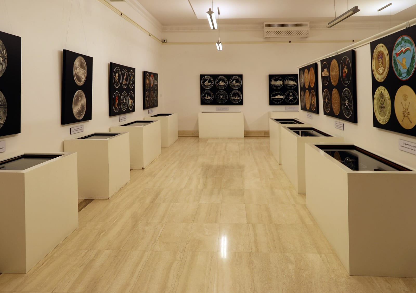 White gallery room at Bait Al Zubair museum in Muscat with framed displays in a row along the walls and low cases.