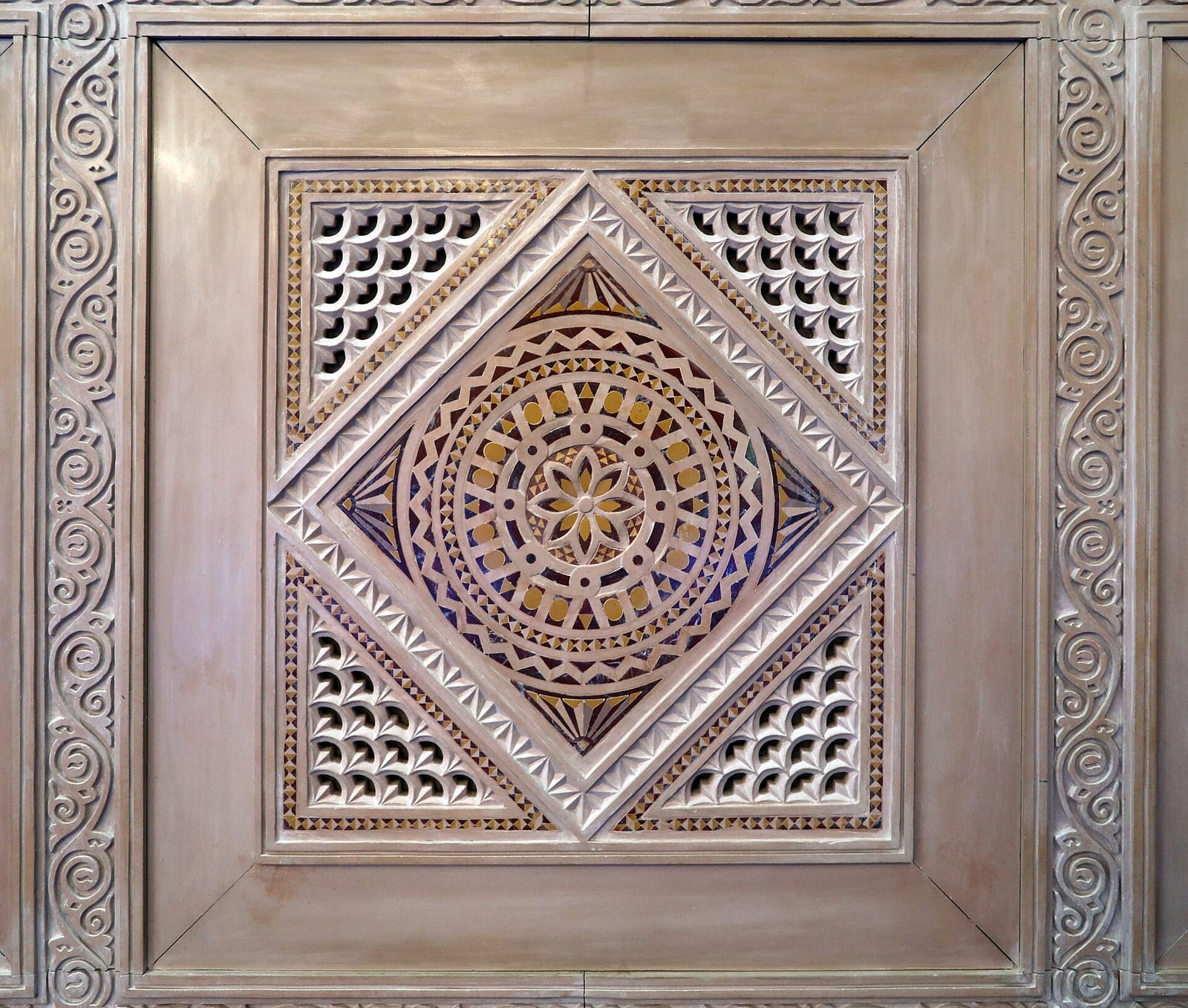 Carved and inlaid geometric marquetry panel with star and lattice motifs in the prayer-hall antechamber of the Sultan Qaboos Grand Mosque.