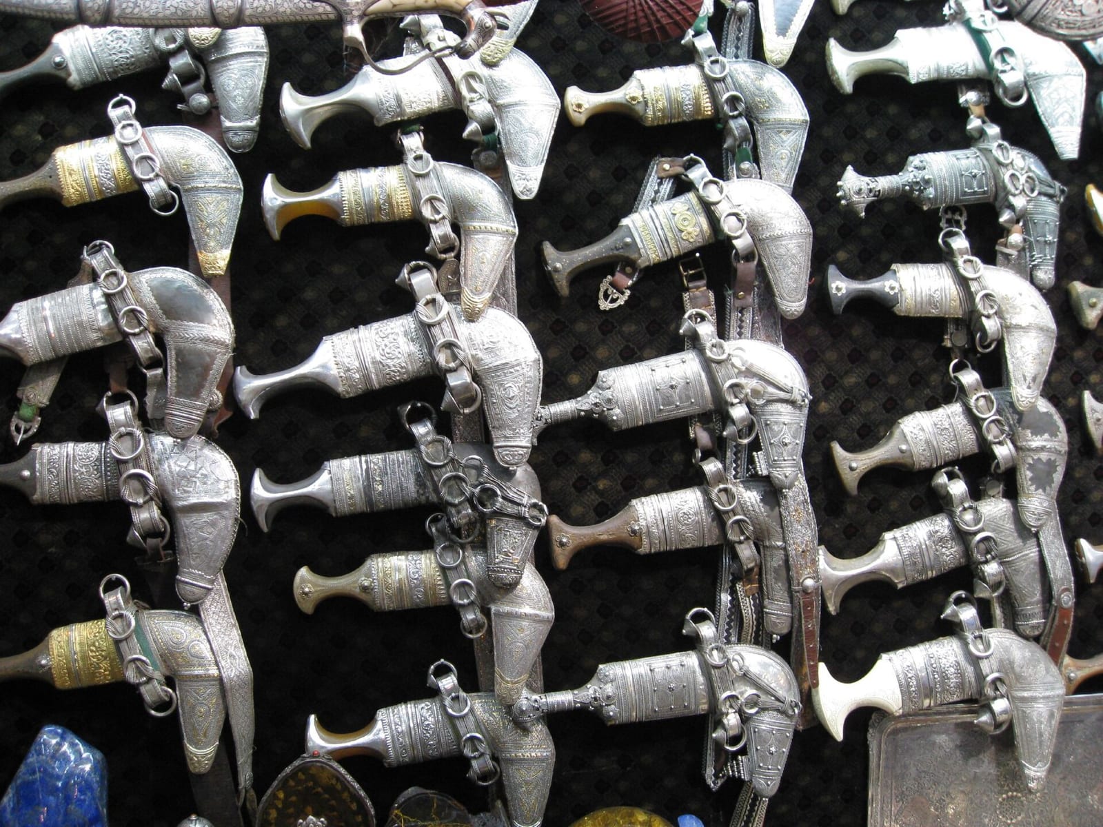 Rows of silver-hilted Omani khanjar daggers hung for sale on a dark wall in the Mutrah Souq, Muscat.