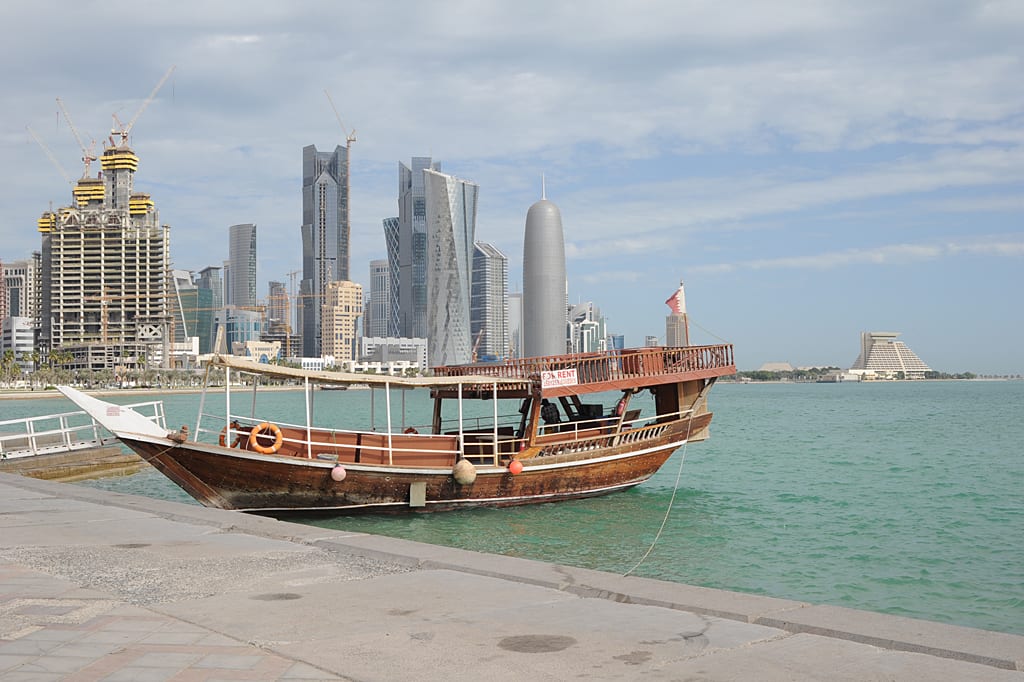 A traditional wooden dhow moored in Doha Bay with the modern glass towers of West Bay behind it, 2011.