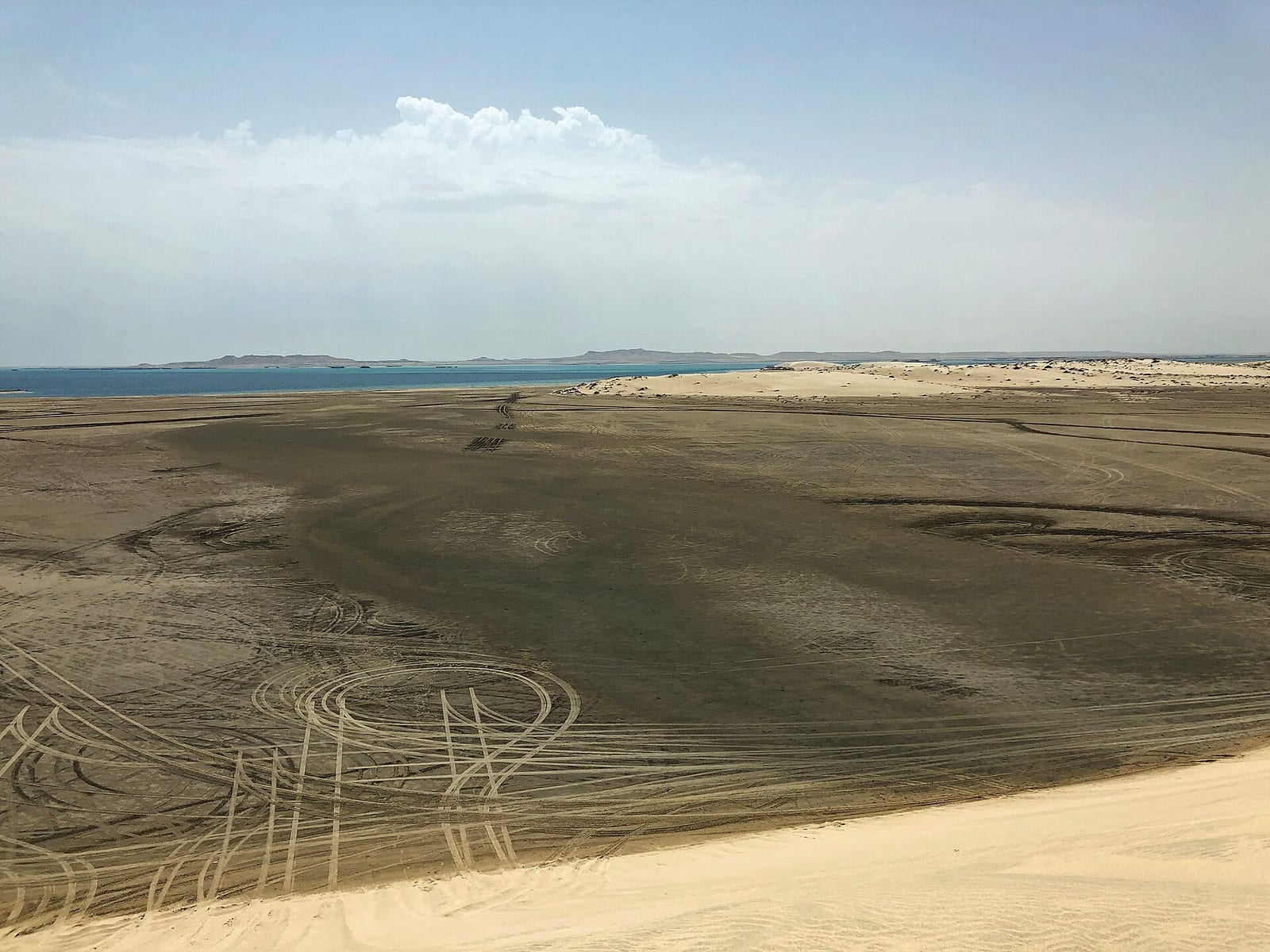 Pale sand dunes meeting the turquoise water of Khor Al Adaid, the Inland Sea in southern Qatar, March 2019.