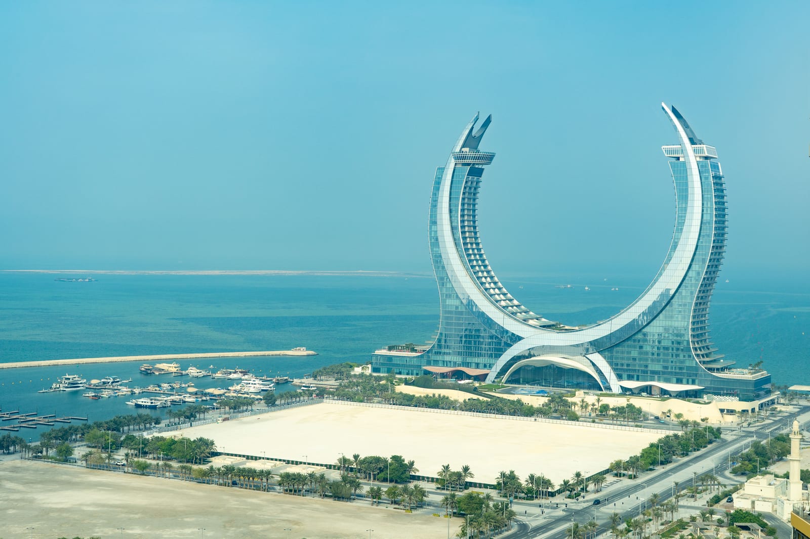 Elevated view of the crescent-shaped Katara Towers in Lusail with the marina and the Gulf beyond.
