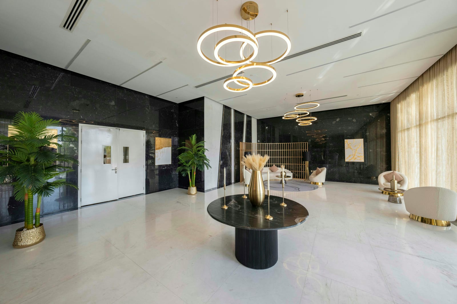Marble-clad entrance lounge of a Lusail home with a black table, white chairs and a tall wall, October 2024.