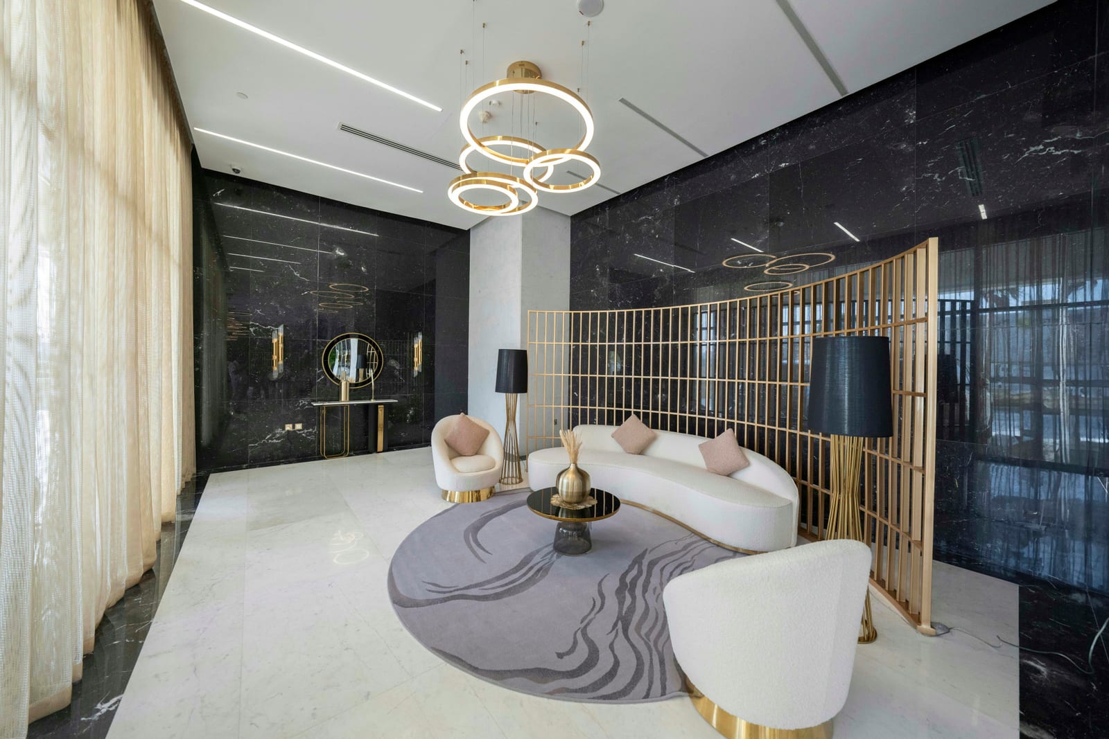 Contemporary Lusail reception room with white sofas, black marble, gold detailing and a large chandelier, October 2024.