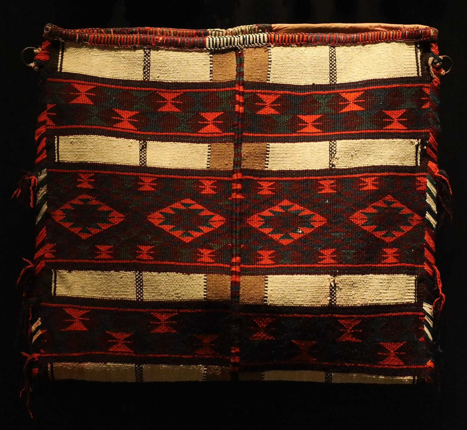 Nineteenth-century Qatari sadu-woven camel bag in red, black and white geometric bands, National Museum of Qatar, November 2023.