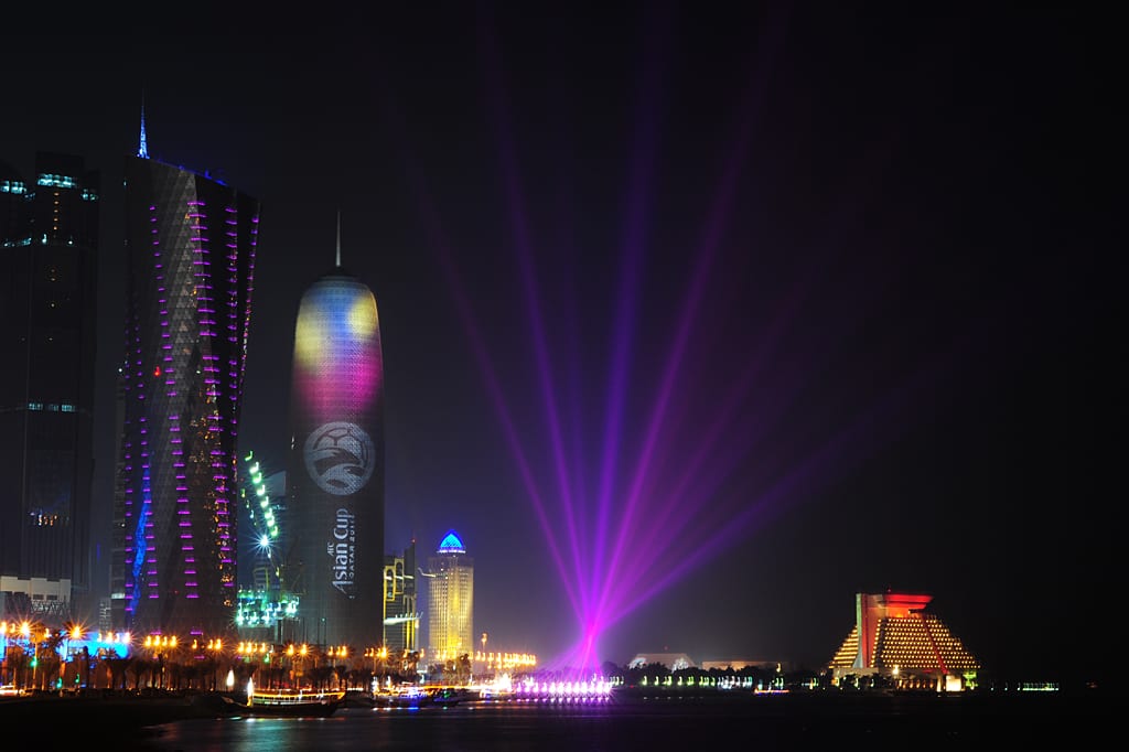 The illuminated office towers of West Bay, Doha, reflected in the water of the Corniche at night, 2011.