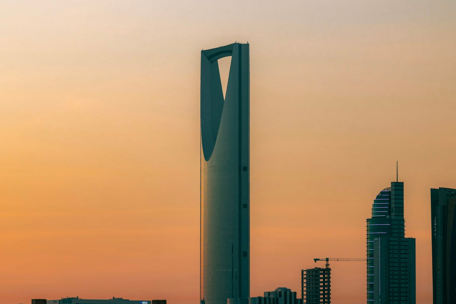 Kingdom Centre tower in Riyadh silhouetted against a warm orange evening sky, 2023.