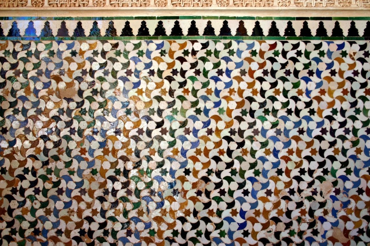 Geometric interlaced tile tessellation in the Alhambra, Granada, in blue, green, ochre and white glazed ceramic.