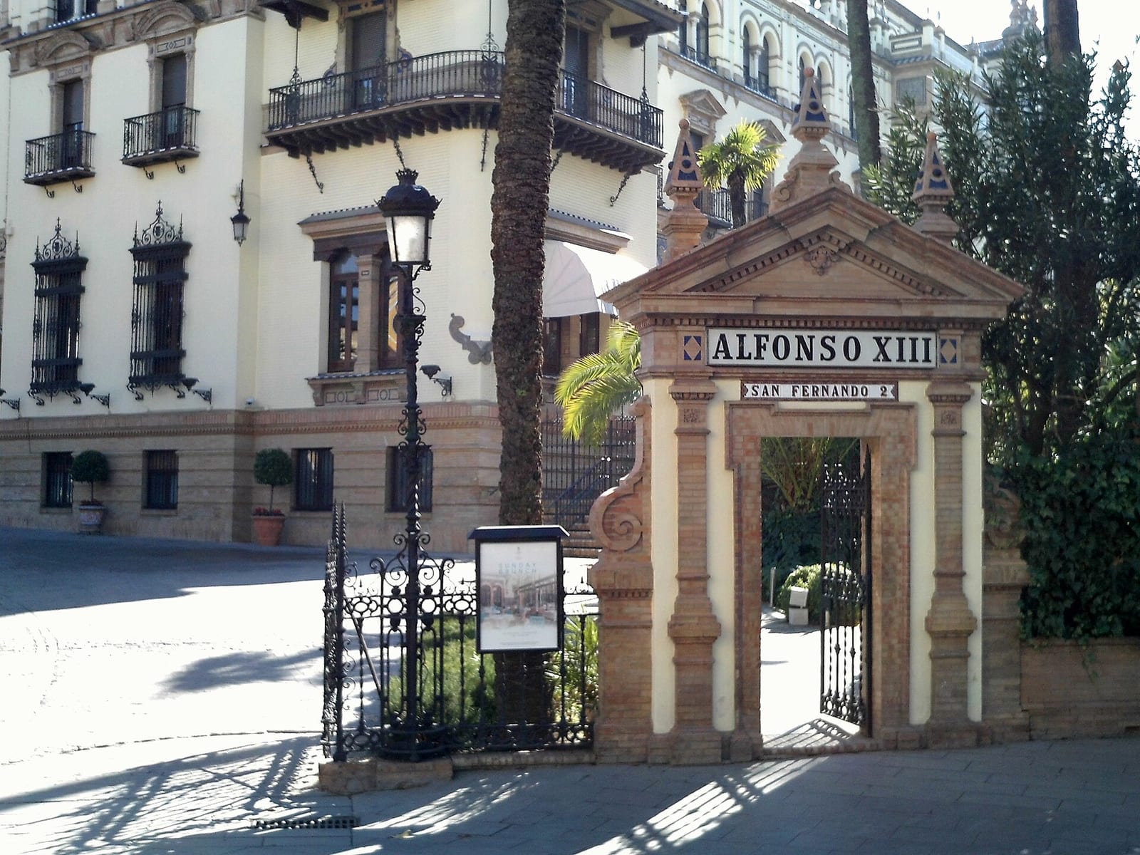 Brick and stone facade of the Hotel Alfonso XIII in Seville, a 1920s grand hotel with arched windows and palm trees.