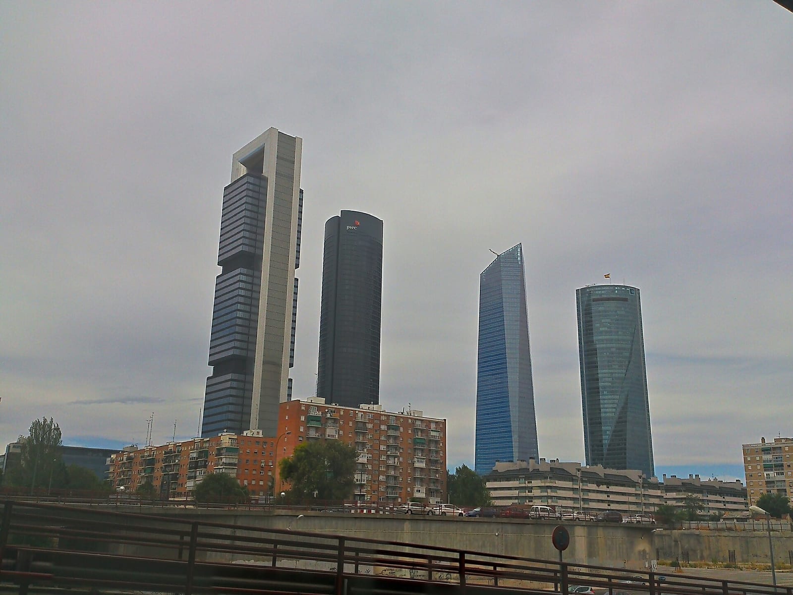 Madrid skyline at dusk with the four Cuatro Torres business towers rising above the low rooftops of the northern districts.