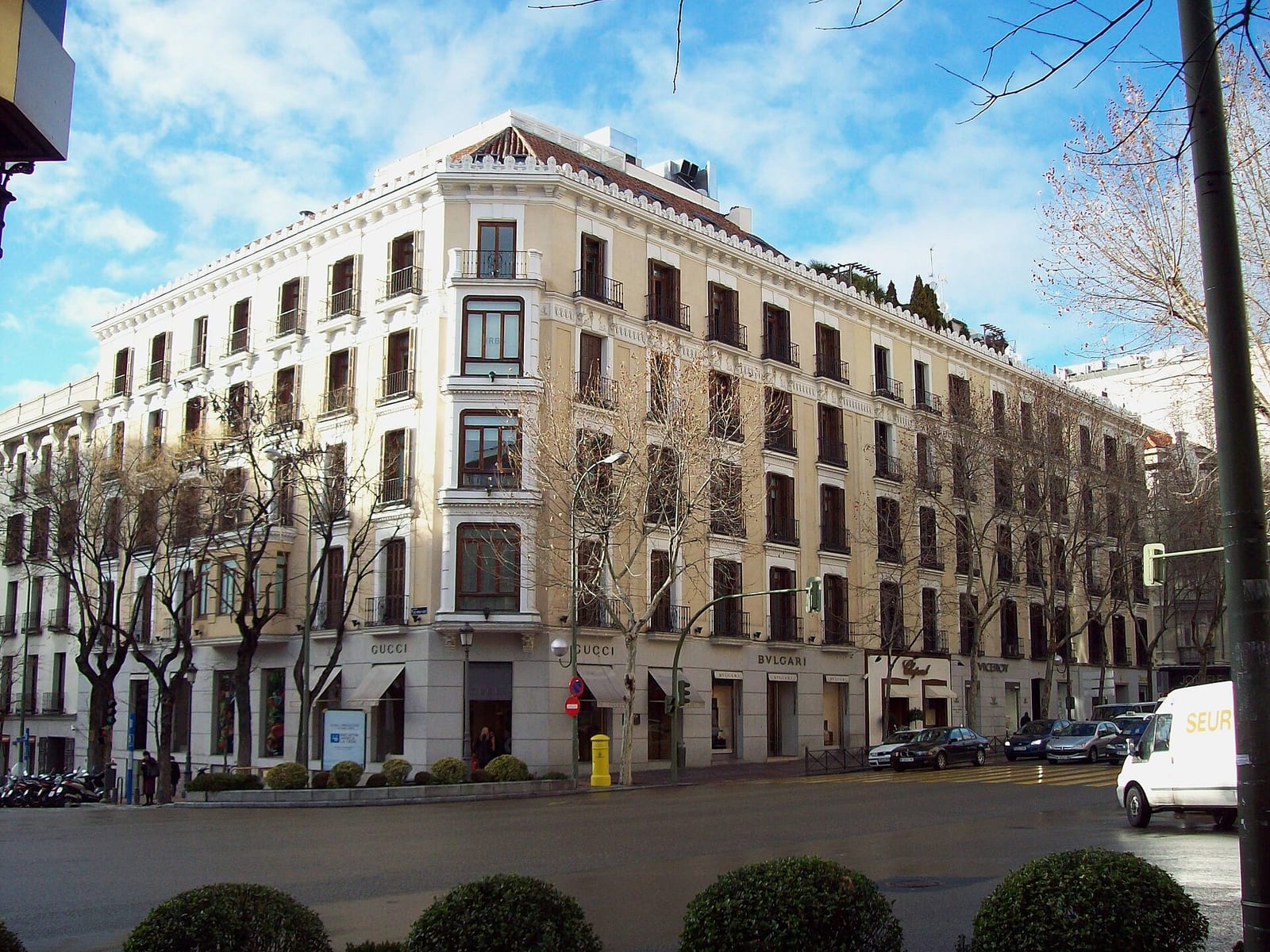 Stone facade of a 1900 apartment building at Calle de Serrano 49–51 in Madrid's Salamanca district, with tall balconied windows.