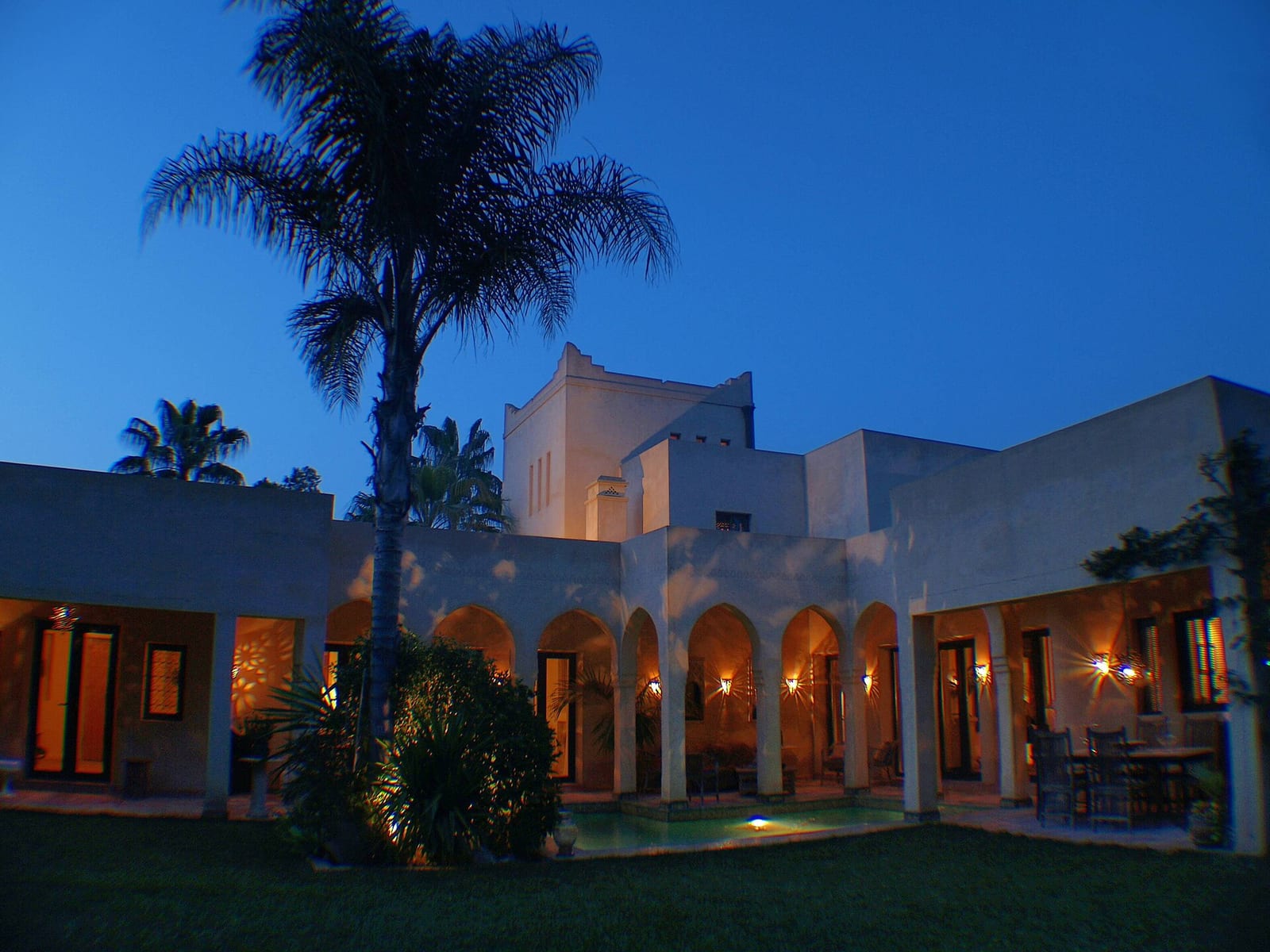 Moorish-style villa in Sotogrande at dusk, its arches and terraces lit against a deep blue sky.