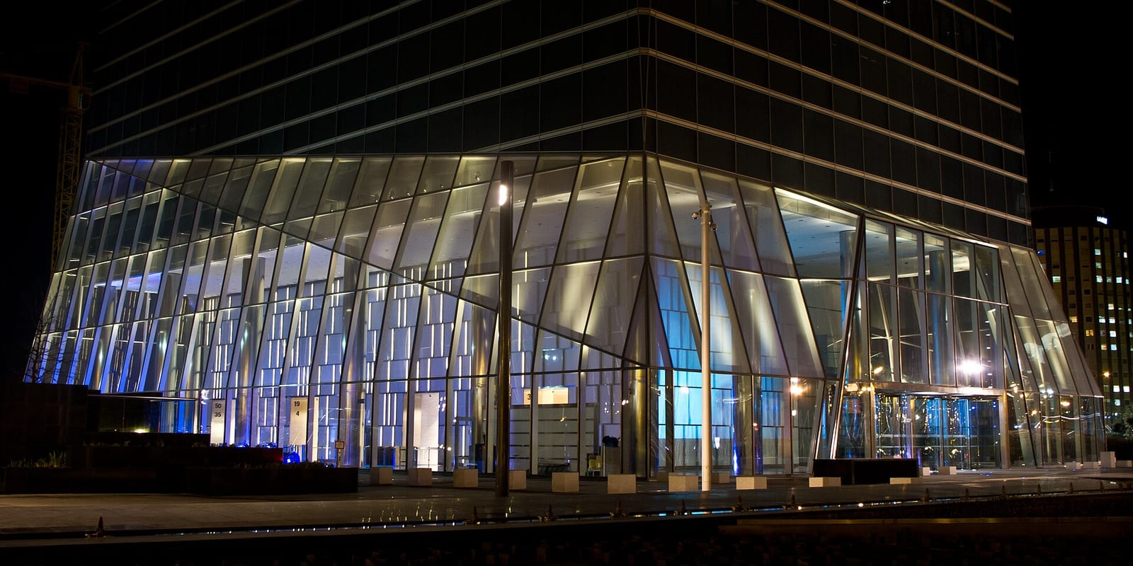 Ground-floor lobby of the Torre de Cristal in Madrid, a tall glazed hall with stone floor and steel columns.