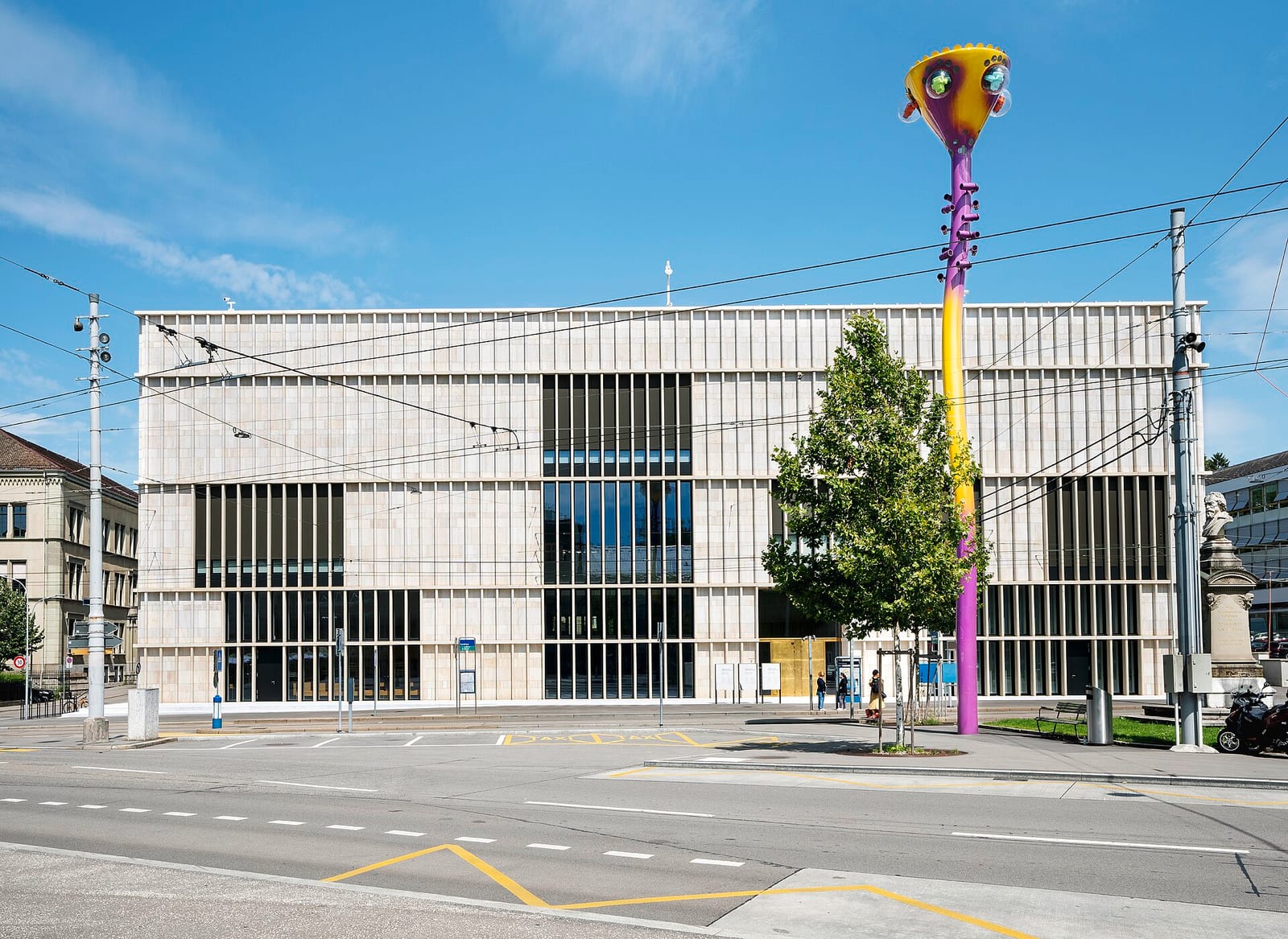 The limestone-fin façade of David Chipperfield's Kunsthaus Zürich extension on Heimplatz, with a tall sculpture in front.