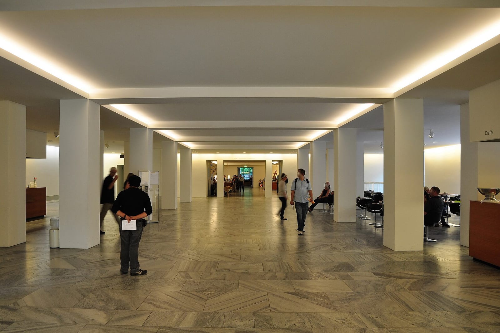 The wide marble-floored entrance hall of the Kunsthaus Zürich with a low coffered ceiling and visitors walking through.
