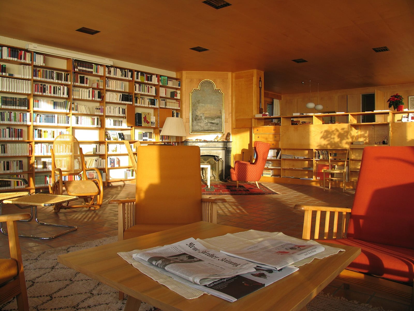 A book-lined living room at the Übersetzerhaus Looren in canton Zürich, with a wooden ceiling, armchairs and warm lamplight.