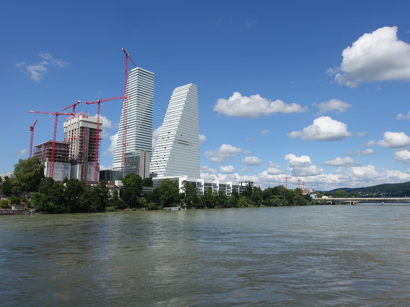 The two white Roche towers rising over the Rhine in Basel, one still under construction, seen from the St. Alban bank.