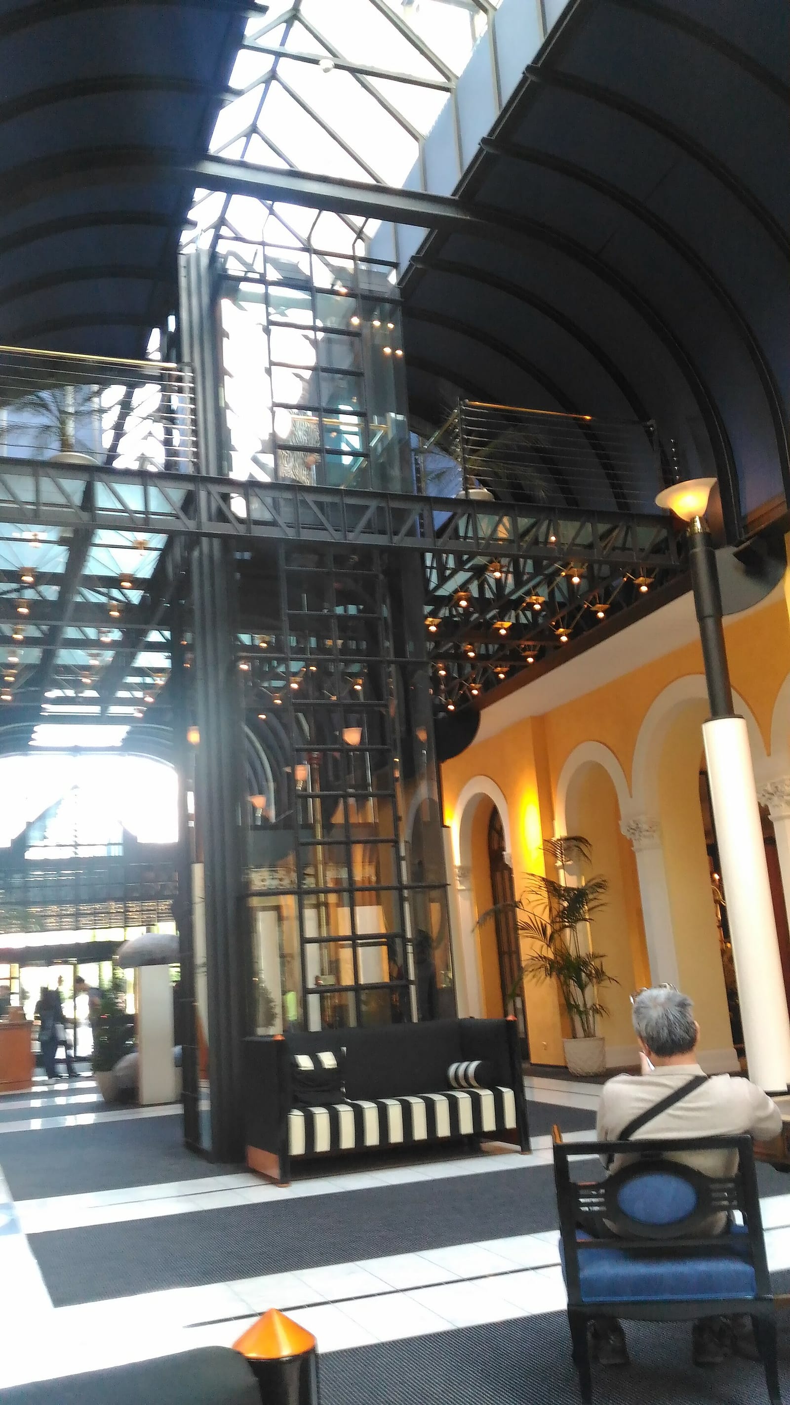 The glazed colonnaded hall of the Victoria-Jungfrau Grand Hotel in Interlaken, with tall arches, warm stone and a black-and-white floor.