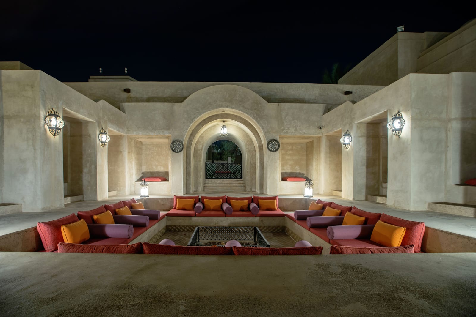 Courtyard of the Bab Al Shams desert resort near Dubai at dusk, arched walkways and warm ambient lighting on sand-coloured walls.
