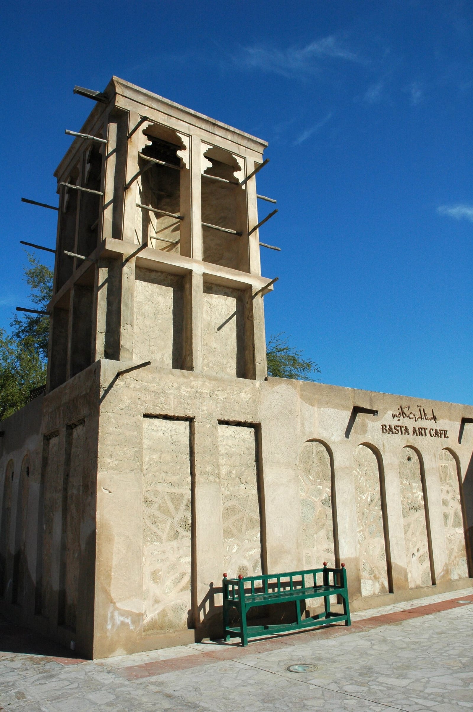 Traditional coral-stone wind tower (barjeel) in the Al Fahidi historical district of Dubai against a blue sky.