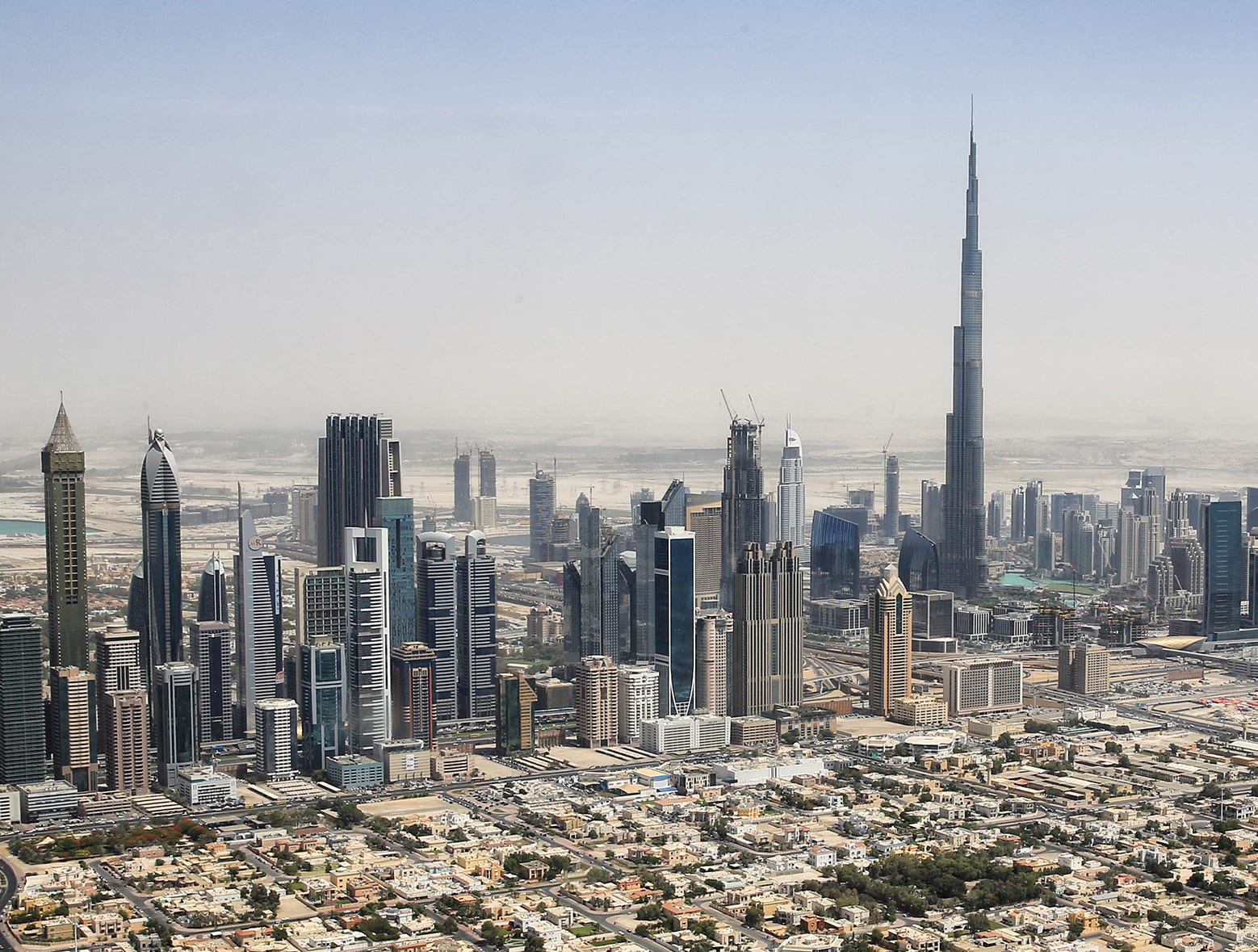 Aerial view of Downtown Dubai from a helicopter, the Burj Khalifa rising above a dense cluster of glass towers, May 2015.