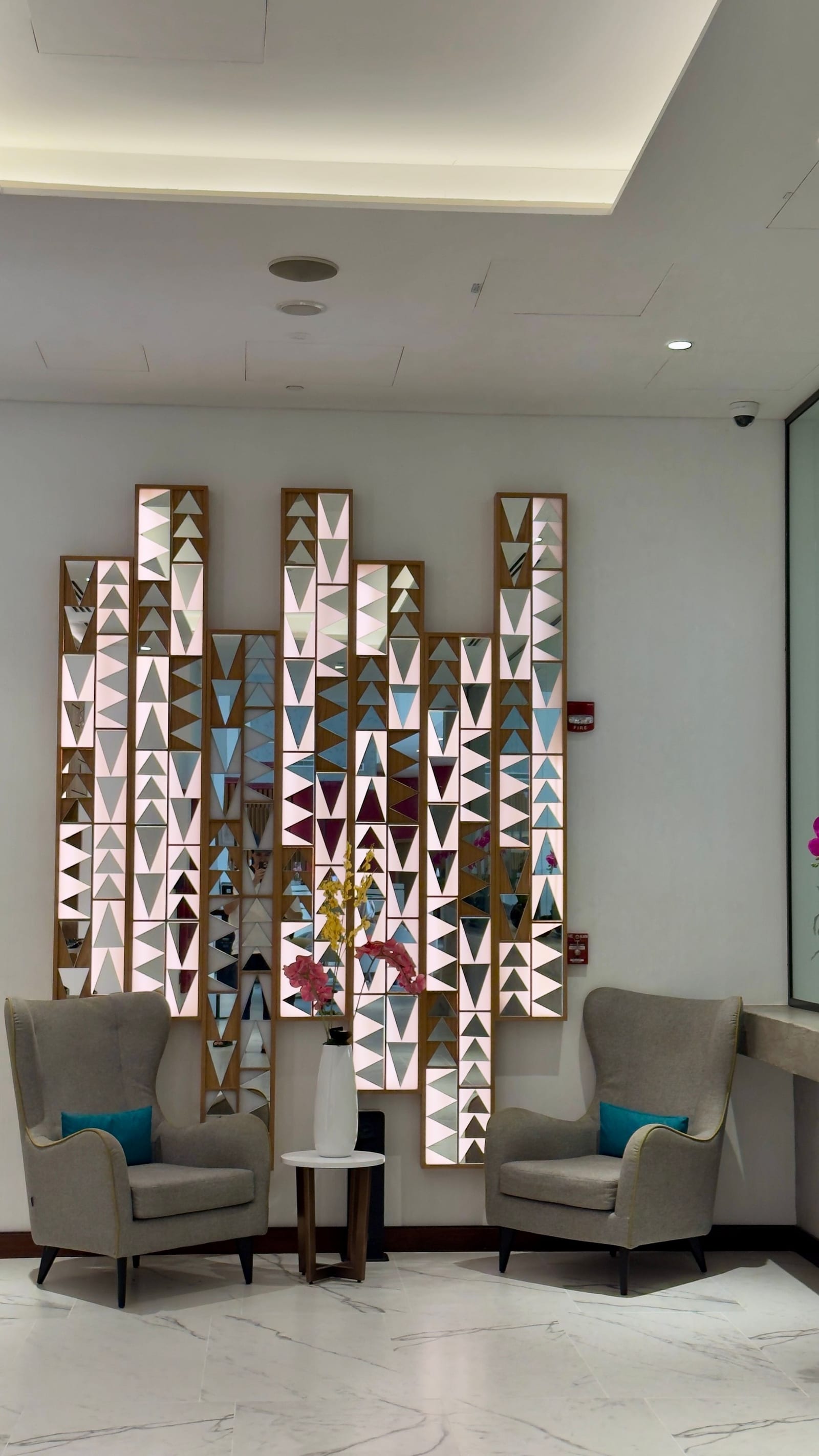 Sleek contemporary Dubai lobby with sculpted wall panels, plush seating and warm lighting.