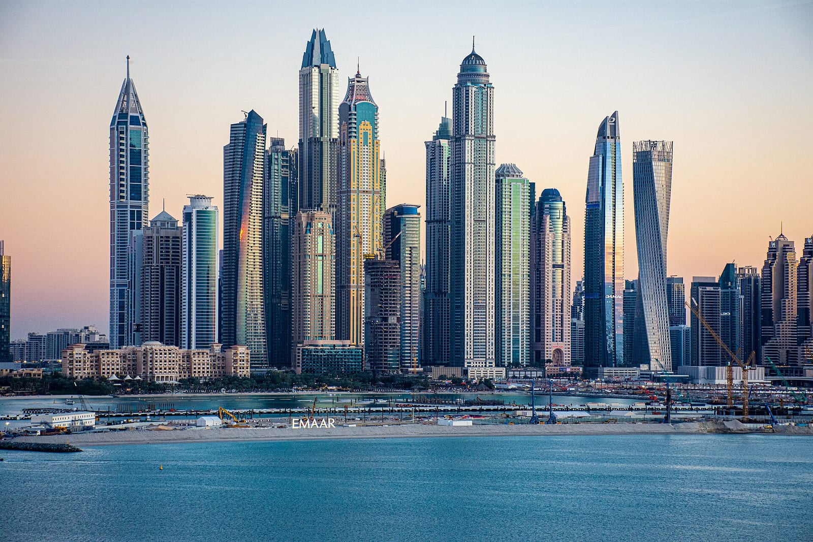 Cluster of Dubai Marina skyscrapers seen across the water, with residential towers packed along the marina front.
