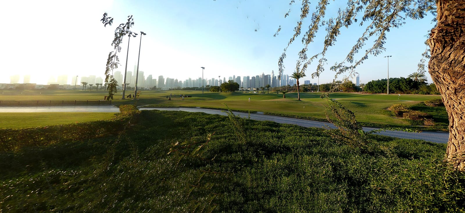 Wide panoramic view over the Emirates Hills golf course in Dubai with large villas lining the fairways under a hazy sky.