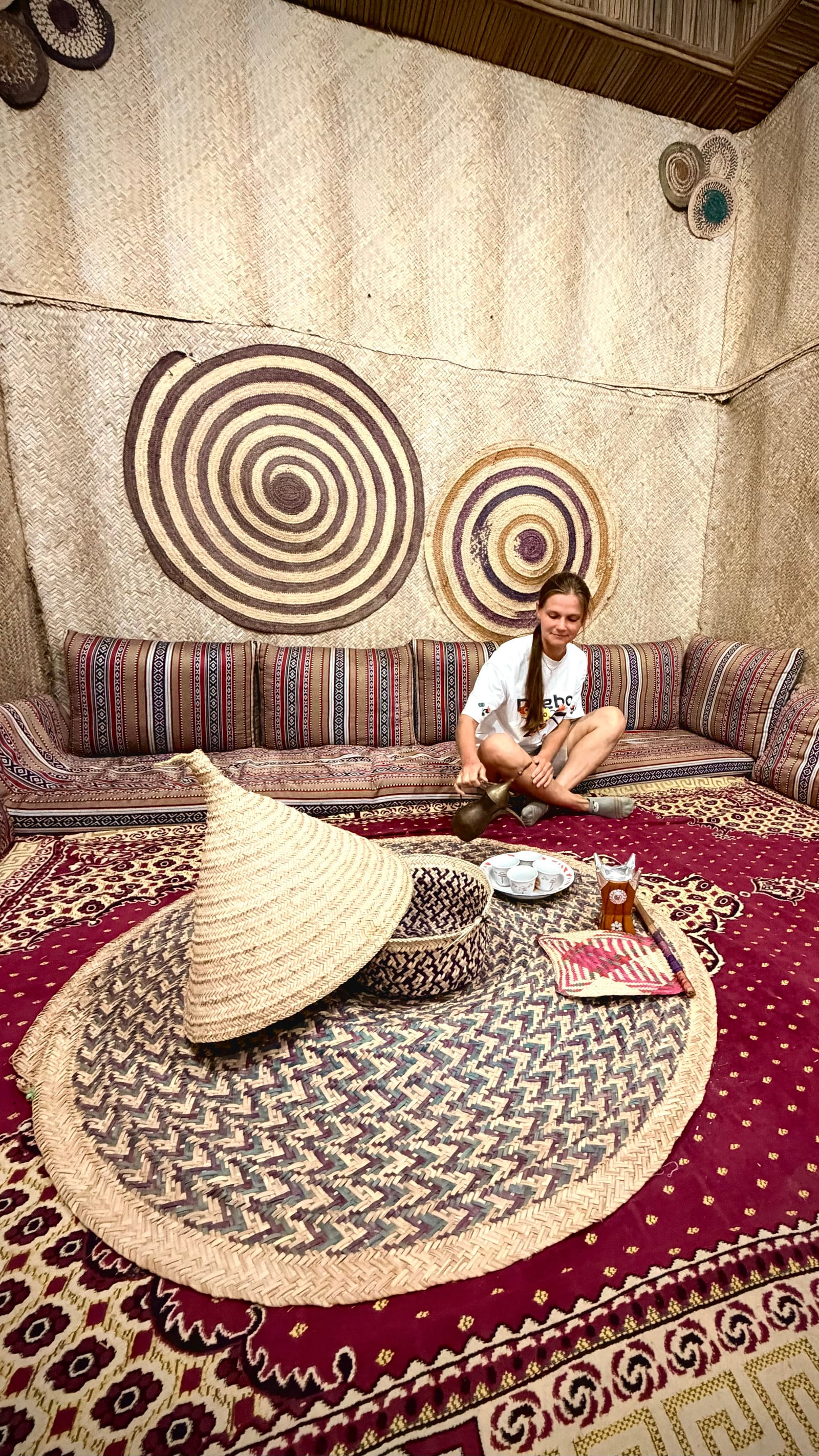 Traditional Emirati majlis with floor cushions, woven textiles, a low table and an Arabic coffee and tea setting.