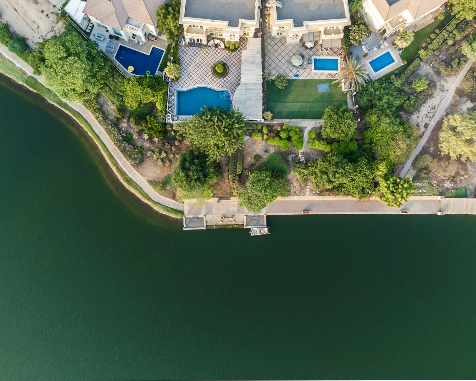 Aerial view of a modern white villa with a swimming pool and palm-lined garden in Jumeirah Islands, Dubai, December 2021.