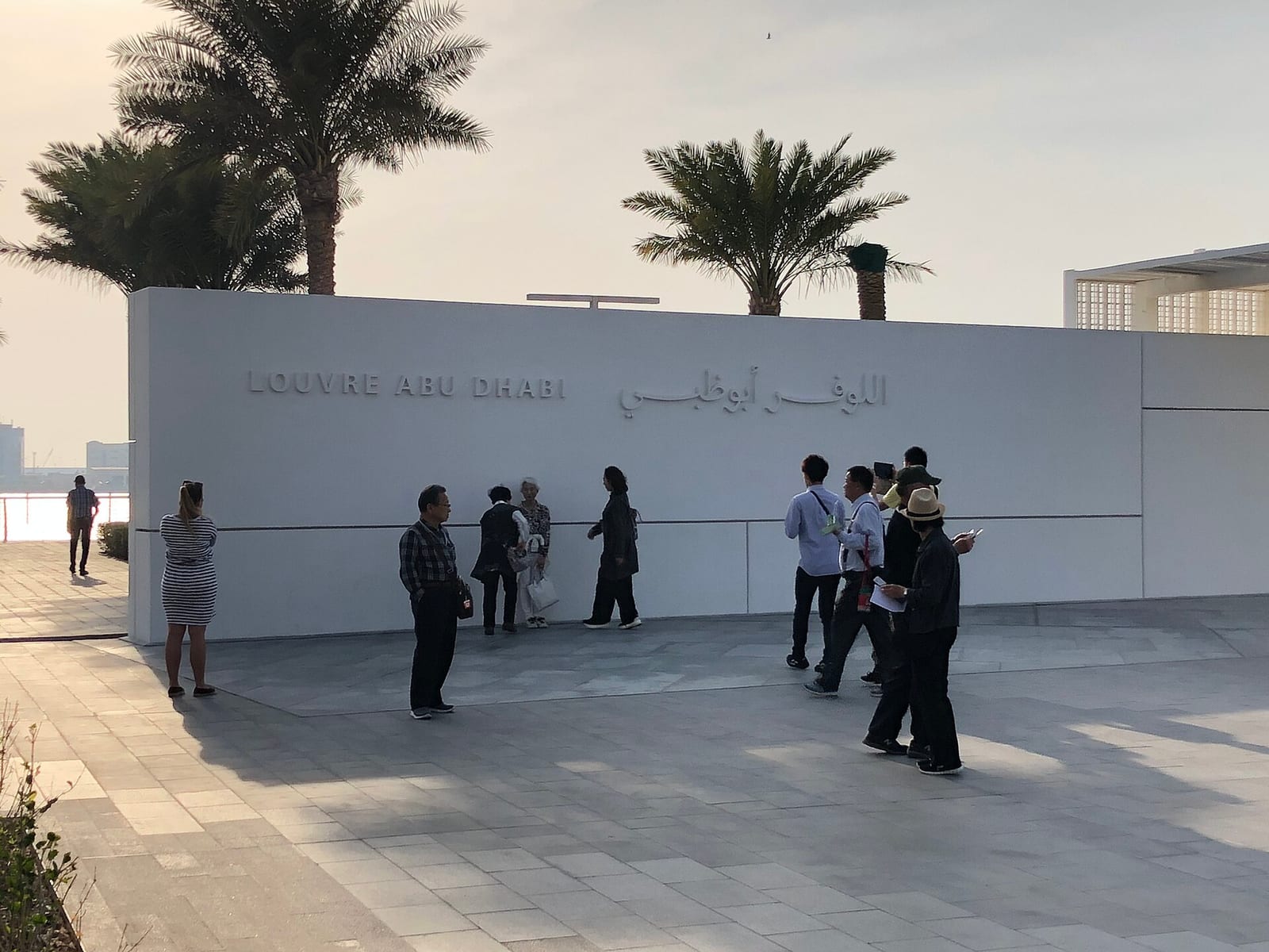Exterior of the Louvre Abu Dhabi on Saadiyat Island, the low silver dome by Jean Nouvel hovering above white galleries and water.