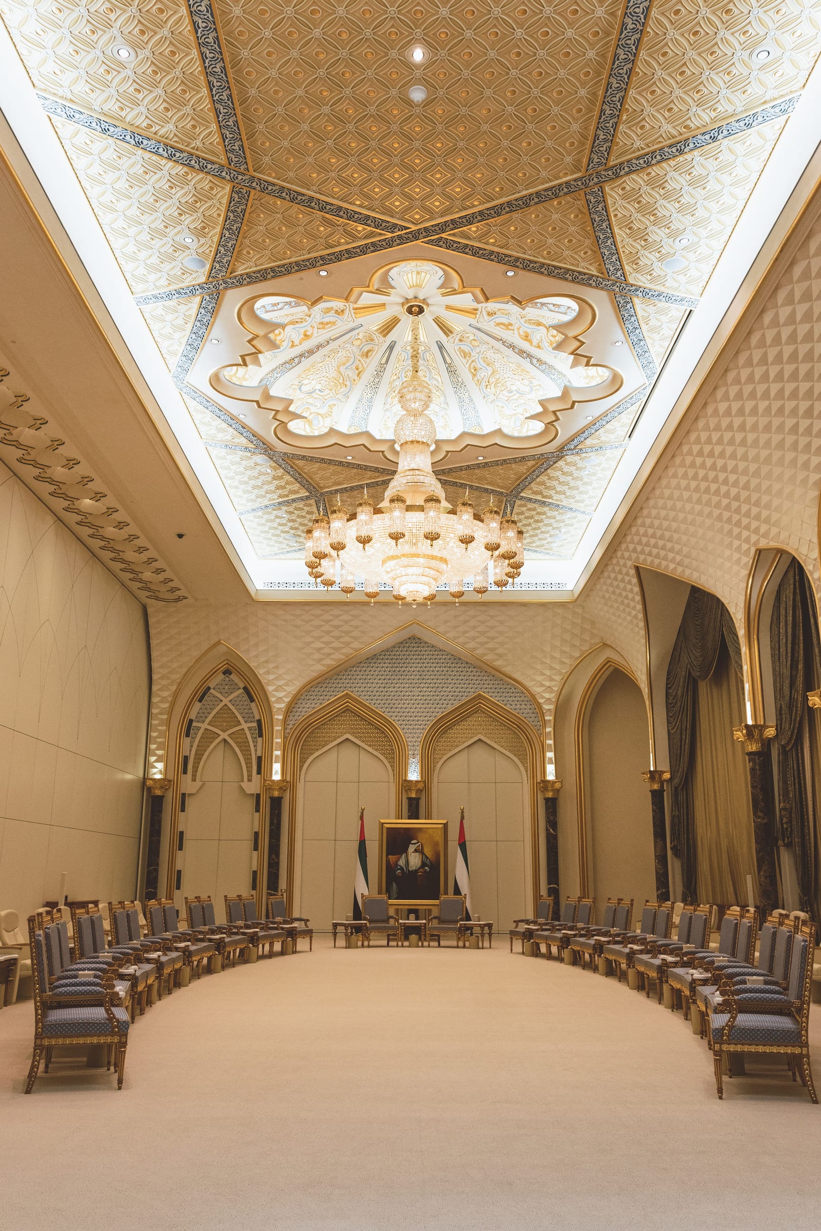 Opulent domed hall inside Qasr Al Watan presidential palace in Abu Dhabi, white and gold arches, marble floor and patterned ceiling.