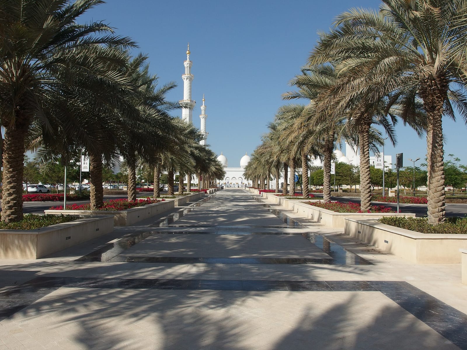 Sheikh Zayed Grand Mosque in Abu Dhabi, white marble domes and arcaded courtyard reflected in a still pool under a clear sky.