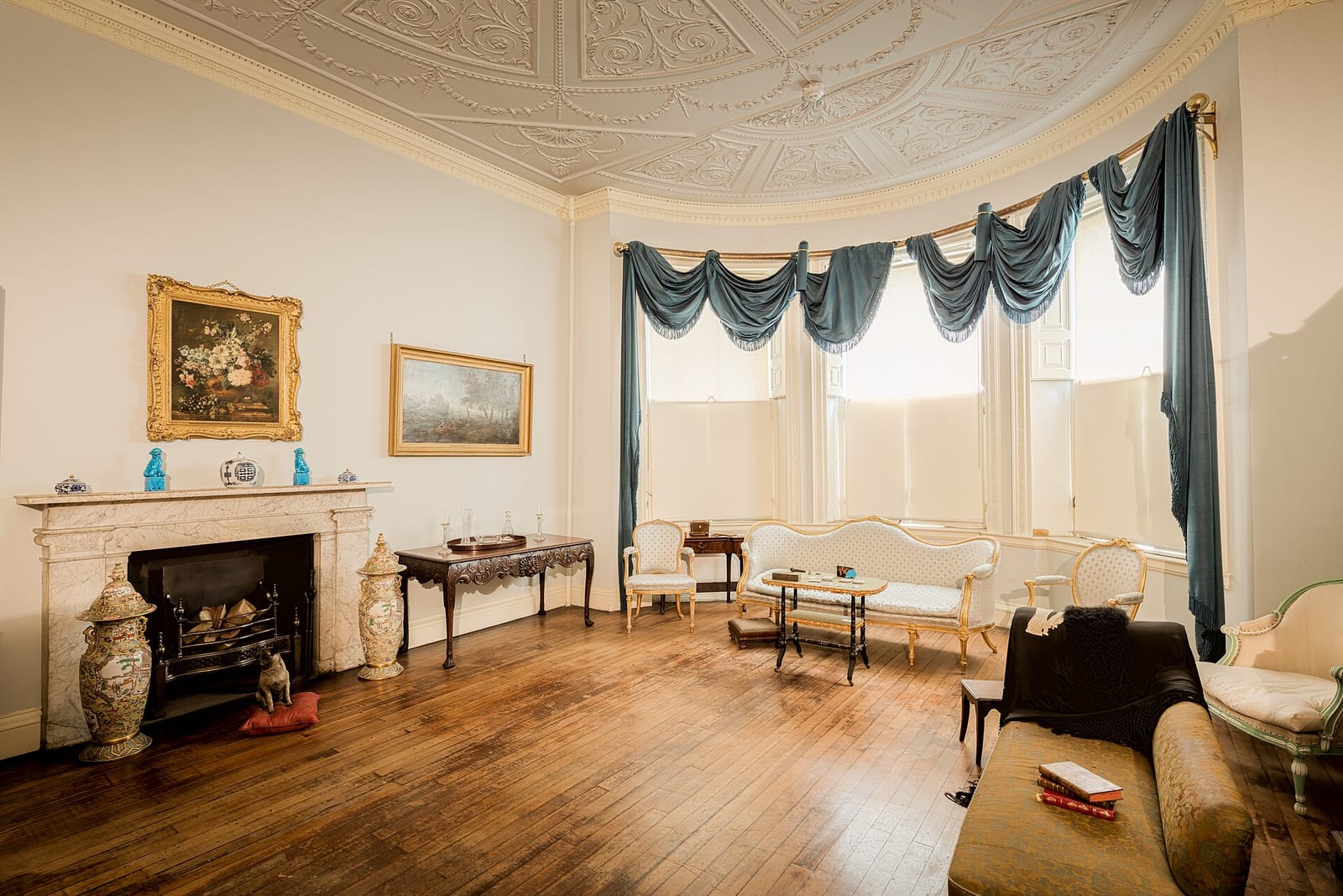 Georgian drawing room at Bolling Hall, Bradford, with a fireplace, panelled walls and framed pictures.