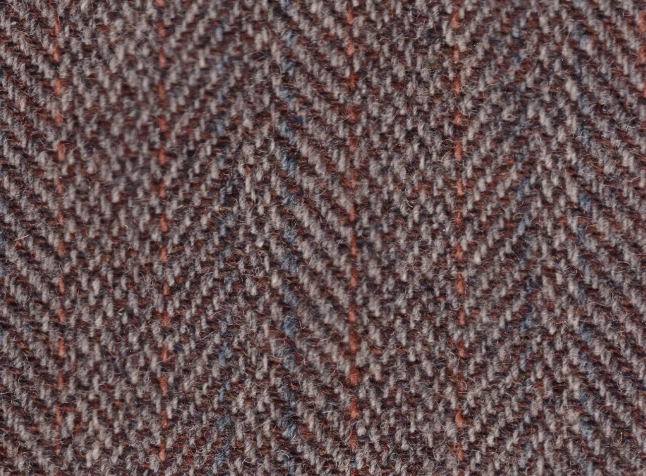 Close-up of woven Harris tweed fabric in muted heather, brown and green tones.