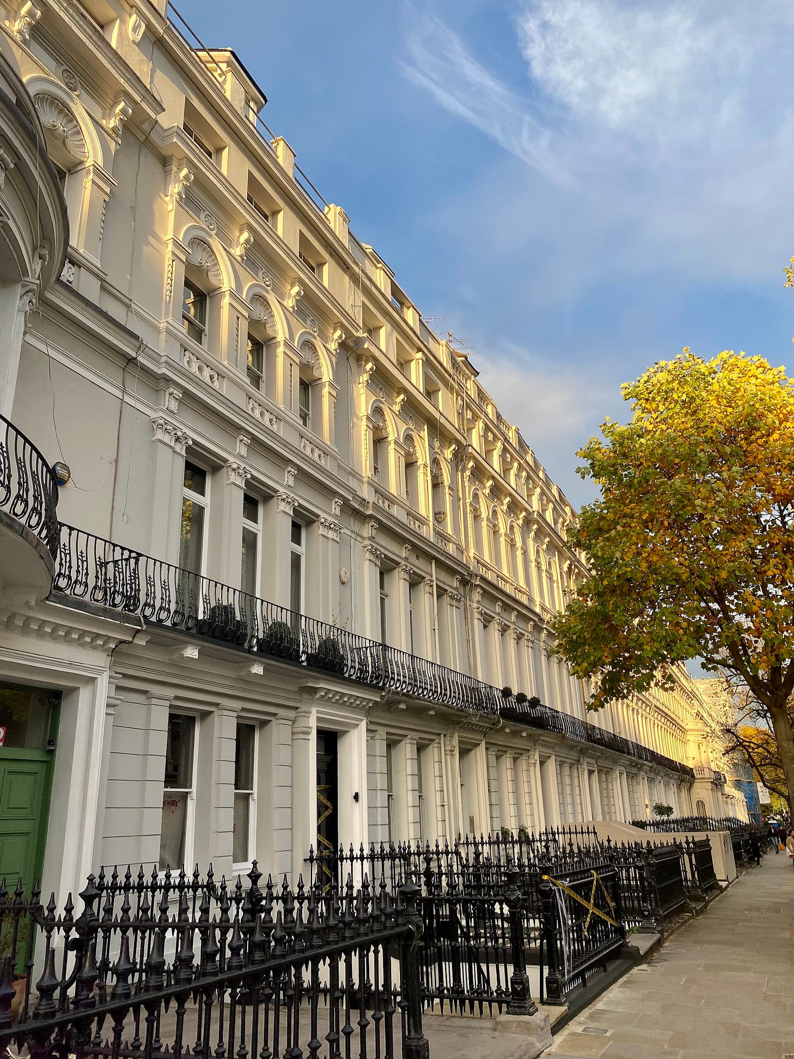 Tall white stucco Victorian houses on Ladbroke Gardens, Notting Hill, with full-height first-floor windows.