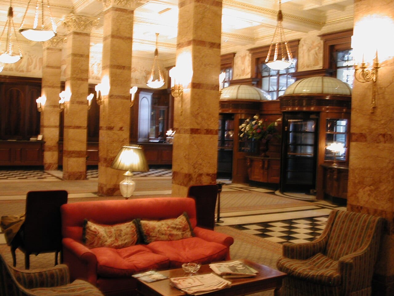 Lobby of the Savoy Hotel, London, with marble floor, columns and framed pictures.