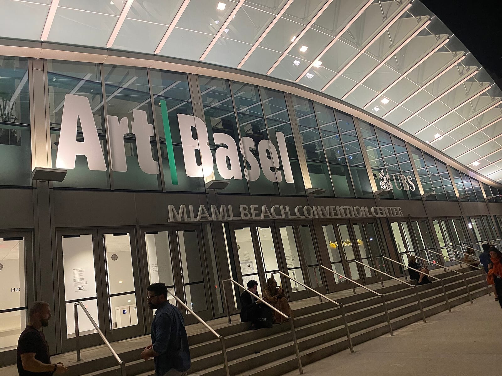 Gallery booths with large paintings and visitors at Art Basel Miami Beach in the convention center, 2021.