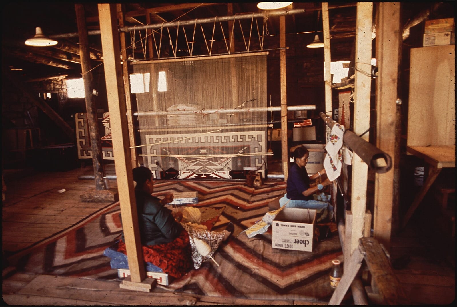 Navajo women weaving a geometric rug at a loom at Hubbell Trading Post, Arizona, May 1972.