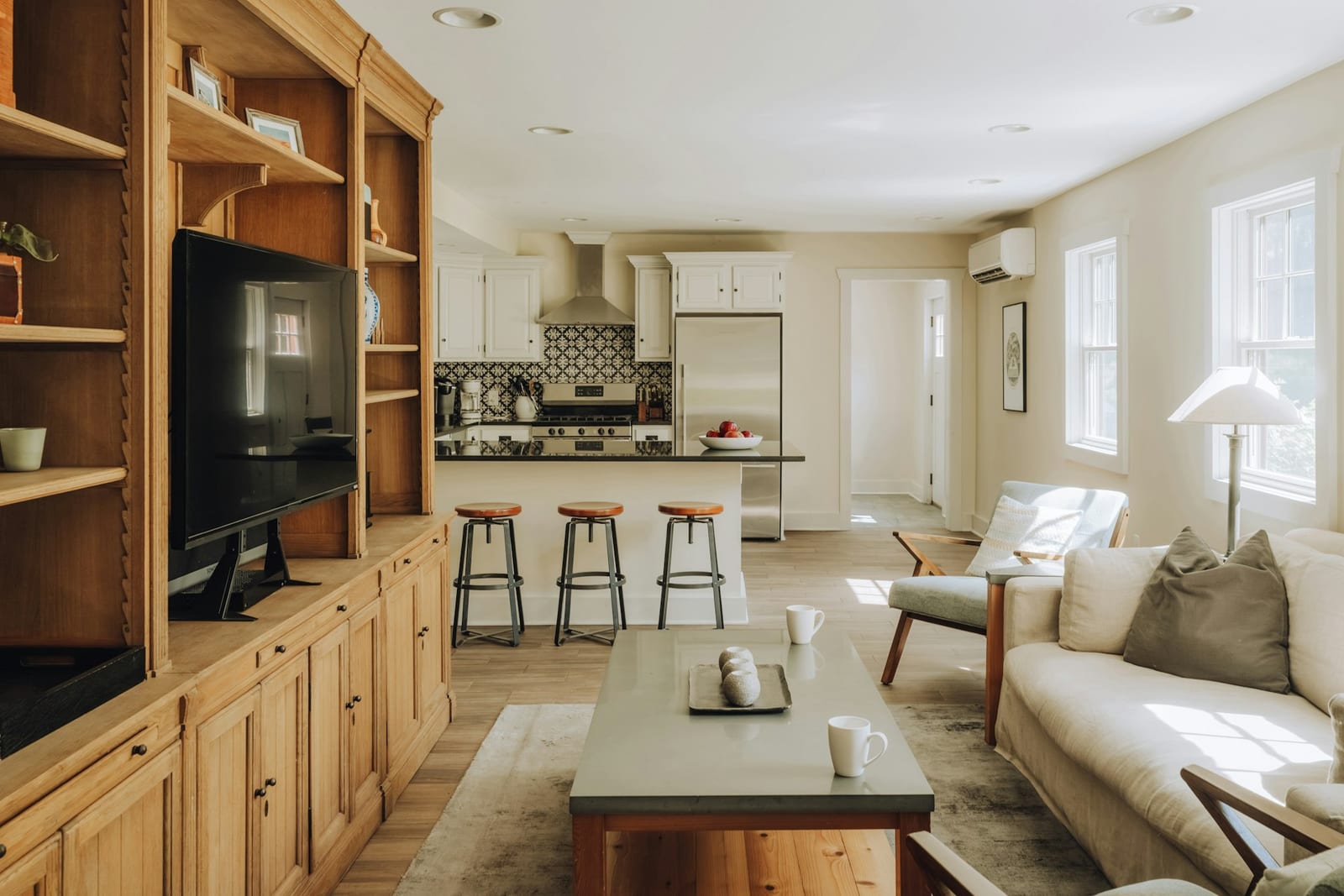 Open-plan living room and kitchen with wooden built-in shelving and a sofa in a country house, Jeffersonville, New York.